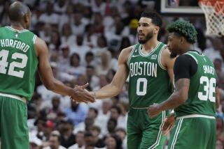 Boston Celtics forward Jayson Tatum (0) and center Al Horford (42) congratulate each other during a break in the second half of Game 4 during the NBA basketball playoffs Eastern Conference finals against the Miami Heat, Tuesday, May 23, 2023, in Miami. (AP Photo/Wilfredo Lee)