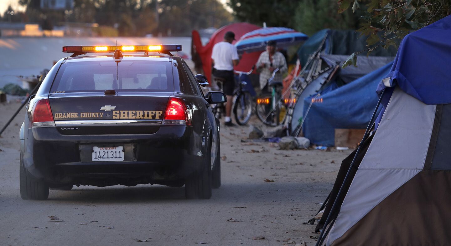 Orange County sheriff’s deputies patrol along the Santa Ana River homeless encampment.