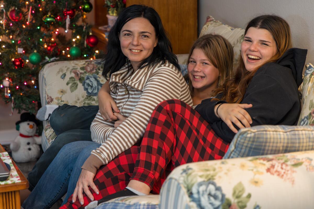 A woman and two girls sitting at home on a couch. 