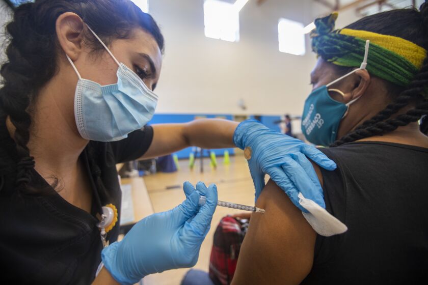 WILMINGTON, CA - JULY 27: Nursing student Joanna Aguilar, left, is giving a vaccination to Maria Isabel Cruz at a vaccination clinic at the Providence Wellness and Activity Center on Tuesday, July 27, 2021 in Wilmington, CA. Escalating COVID-19 cases are threatening a new surge in Southern California . Providence is holding three-day COVID-19 vaccine clinic in Wilmington for people 12 years old and up Tuesday, Wednesday, Thursday, July 27-29. (Francine Orr / Los Angeles Times)