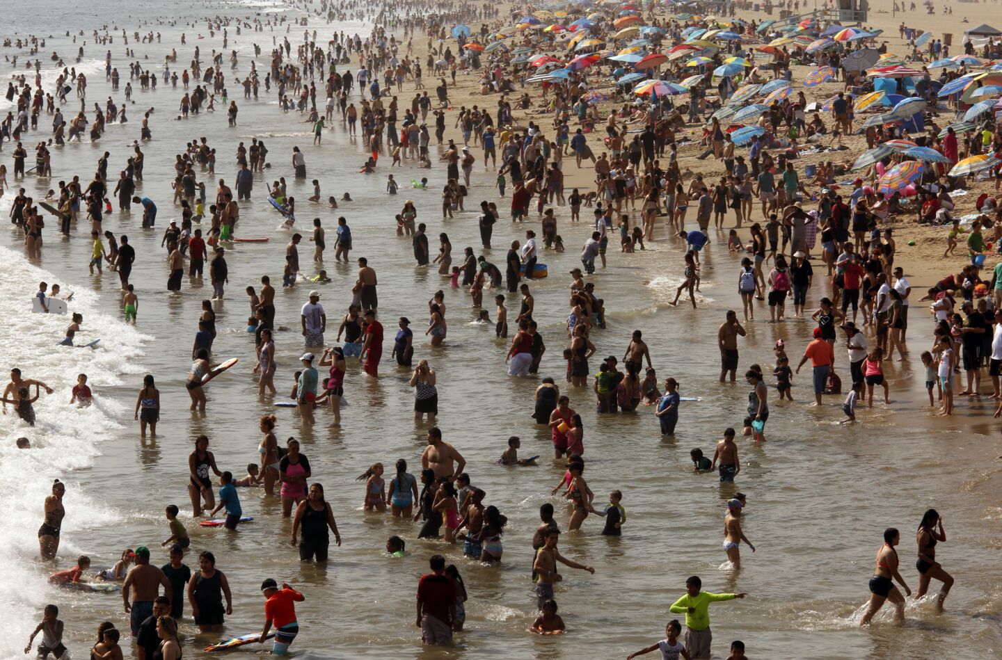 Hundreds of people seek relief from the hot weather Sunday near the Santa Monica Pier.