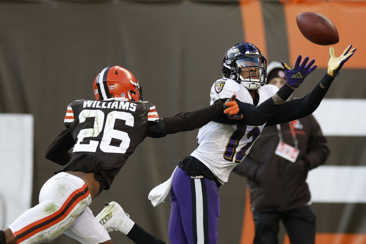 Baltimore Ravens wide receiver Rashod Bateman (12) makes a catch under pressure from Cleveland Browns cornerback Greedy Williams (26) during the second half of an NFL football game, Sunday, Dec. 12, 2021, in Cleveland. (AP Photo/Ron Schwane)
