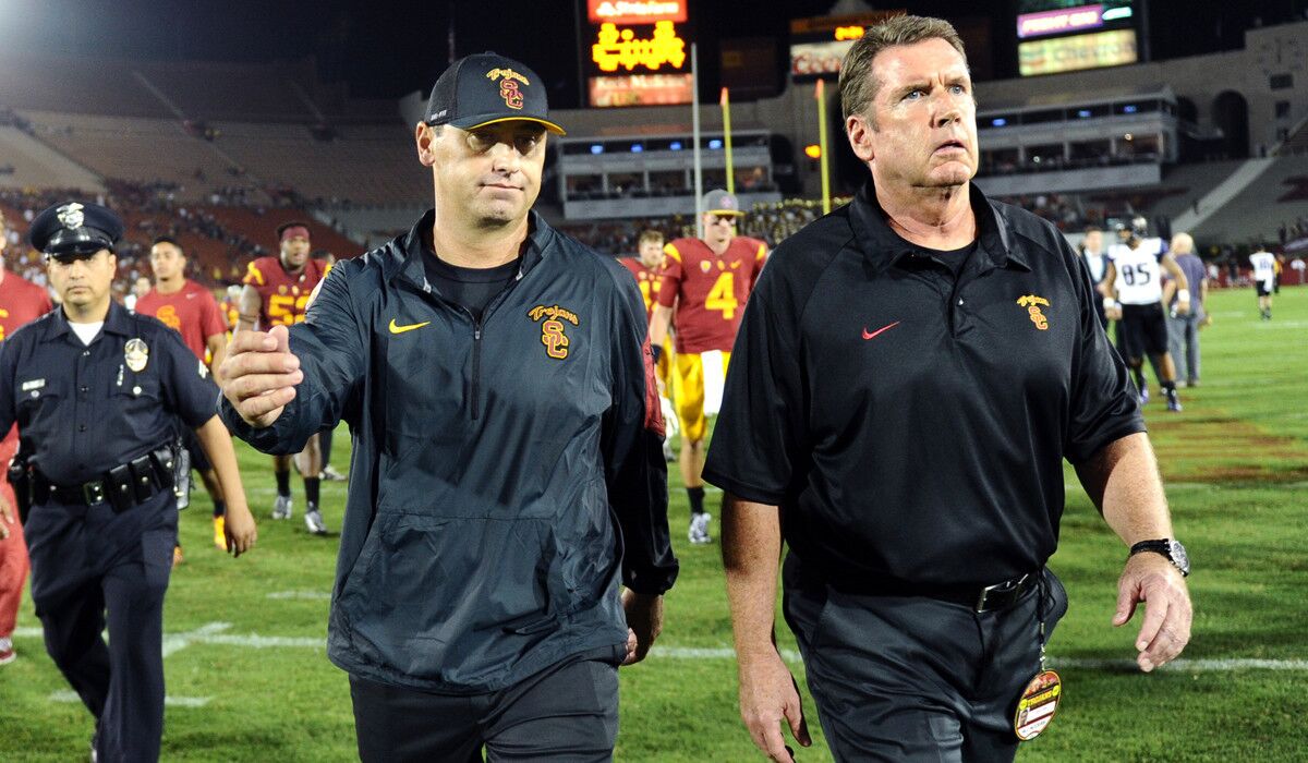 USC head coach Steve Sarkisian, left, walks off the field after losing to Washington at the Coliseum on Thursday.