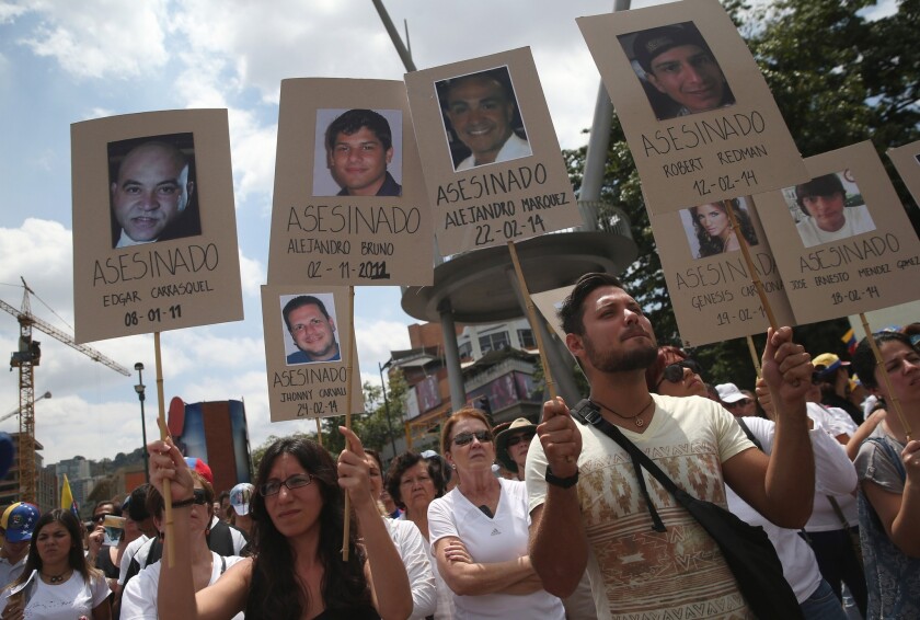 Protesters at an anti-government rally in Caracas, Venezuela, on Friday hold up photos of people they say were killed while demonstrating. The official death toll from over two weeks of violence rose to 17.