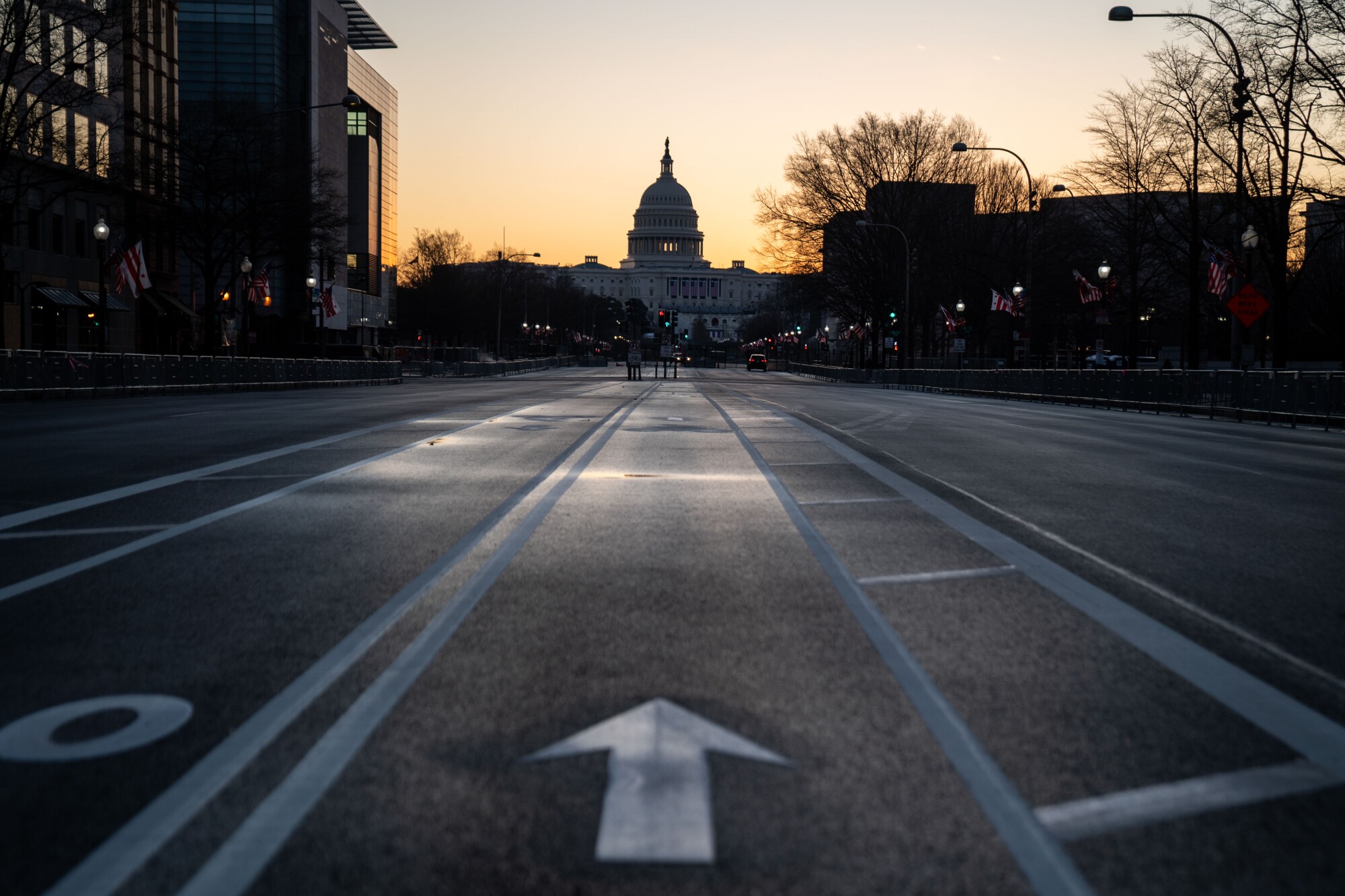 The sun rises behind the U.S. Capitol on Saturday, as seen from Pennsylvania Avenue