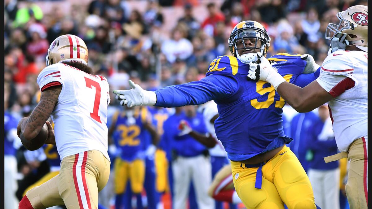 Rams defensive lineman Dominique Easley is held by 49ers Joshua Garnett for a penalty as Colin Kaepernick runs by in the first quarter at the Coliseum.