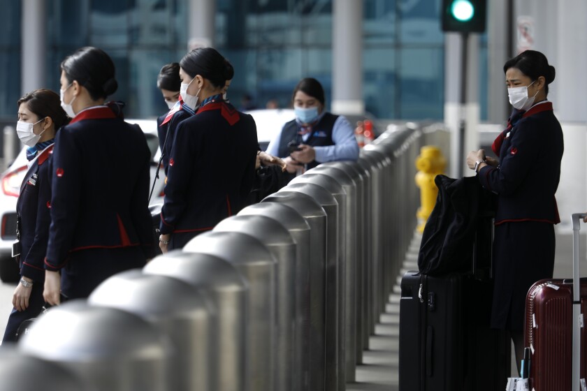 LOS ANGELES, CA - MARCH 24, 2020 - Flight attendants wear masks to ward off the coronavirus at the Tom Bradley International Terminal at LAX in Los Angeles on March 24, 2020. (Genaro Molina / Los Angeles Times)