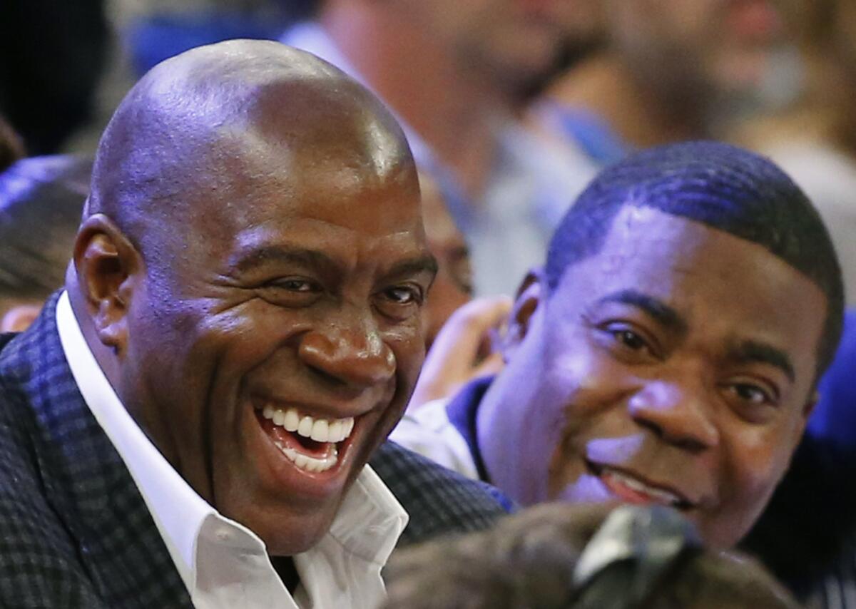 Magic Johnson and comedian Tracy Morgan sit on the sidelines during a game between the Los Angeles Lakers and the New York Knicks at Madison Square Garden on Nov. 8. Johnson is joining the effort to bring the Summer Olympics back to Southern California.