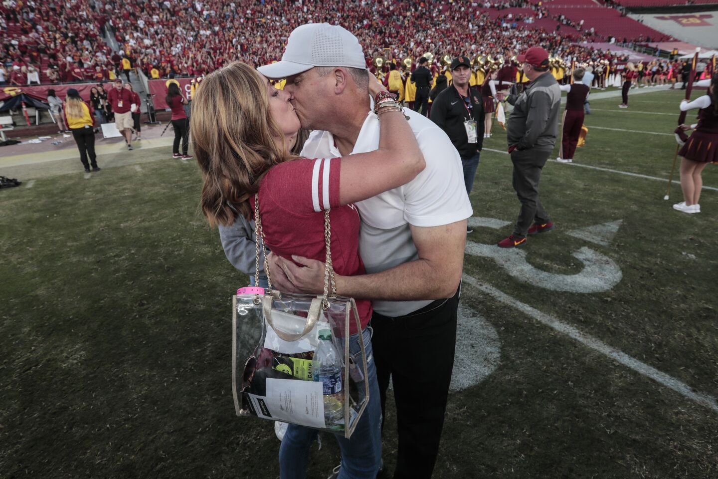 USC head coach Clay Helton shares a kiss with his wife, Angela, at midfield after a 52-35 win over UCLA at the Coliseum on Saturday.