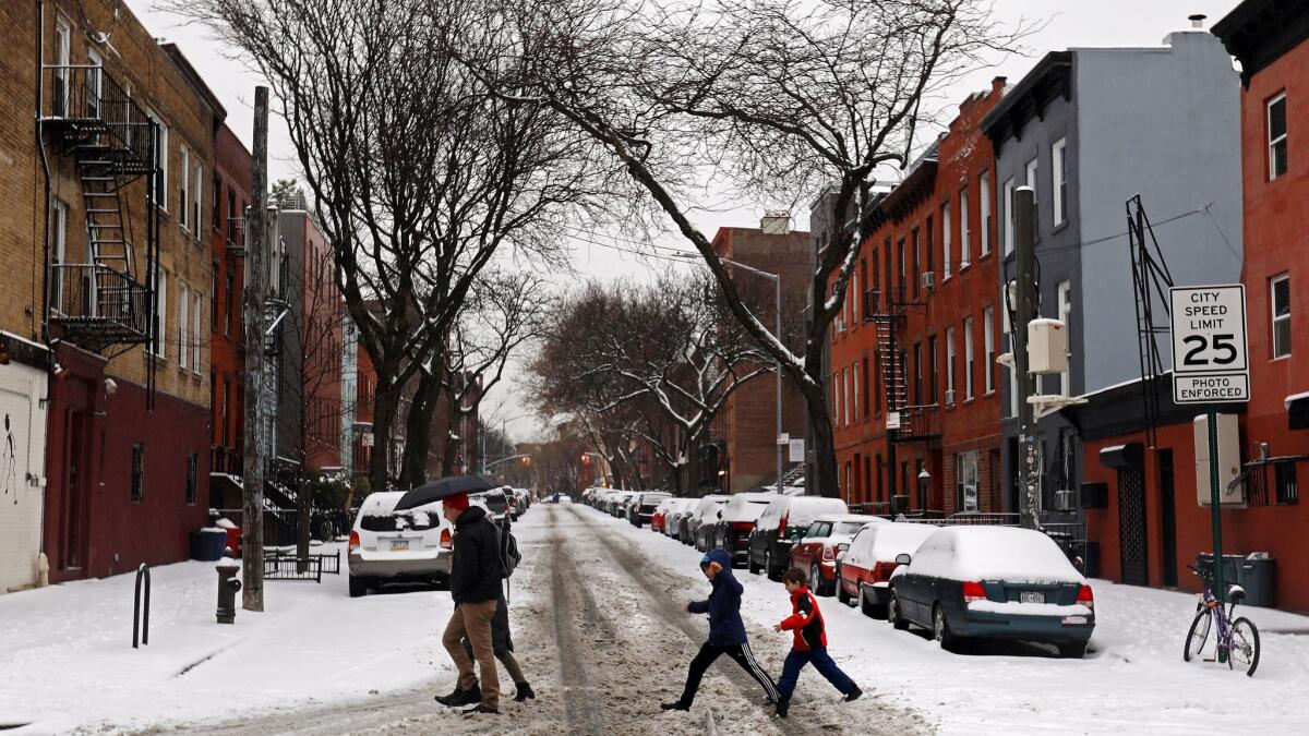 People cross a snowy intersection in the Carroll Gardens neighborhood of Brooklyn, N.Y.
