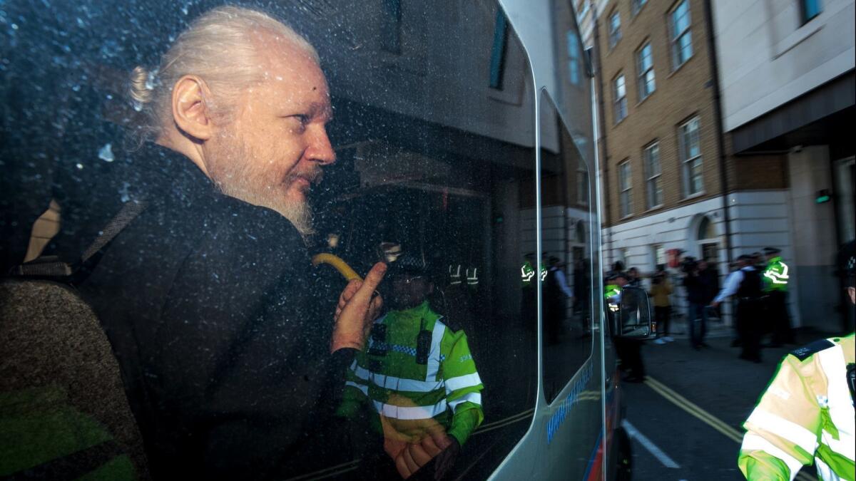 Julian Assange gestures to the media from a police vehicle on his arrival at Westminster Magistrates court in London, England on April 11.