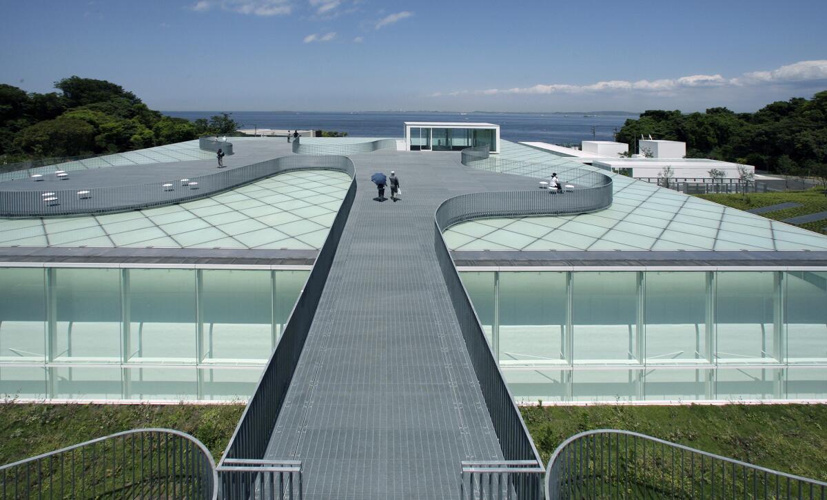 An overhead view shows a horizontal museum building with un undulating pathway on top.