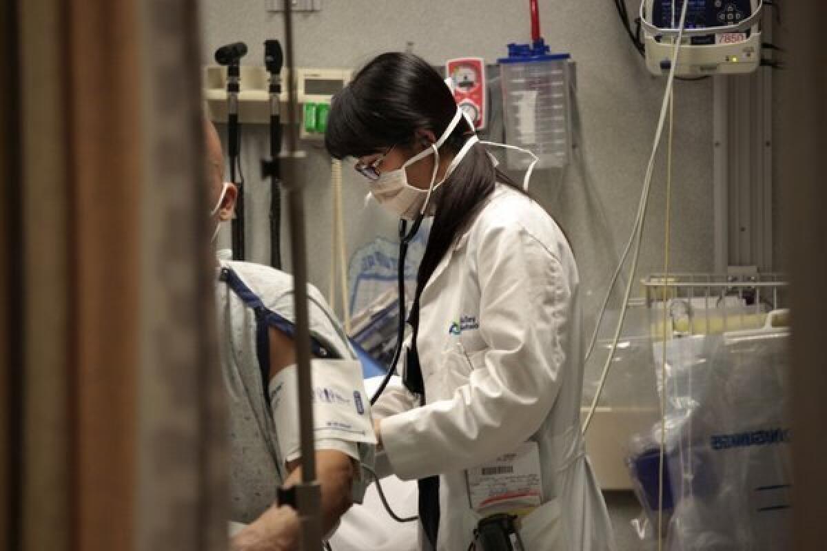 A medical resident treats a patient with flu symptoms at Lehigh Valley Hospital in Allentown, Pa.