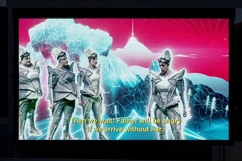 Opera singers in silver space suits are projected against a digital background using a green screen.