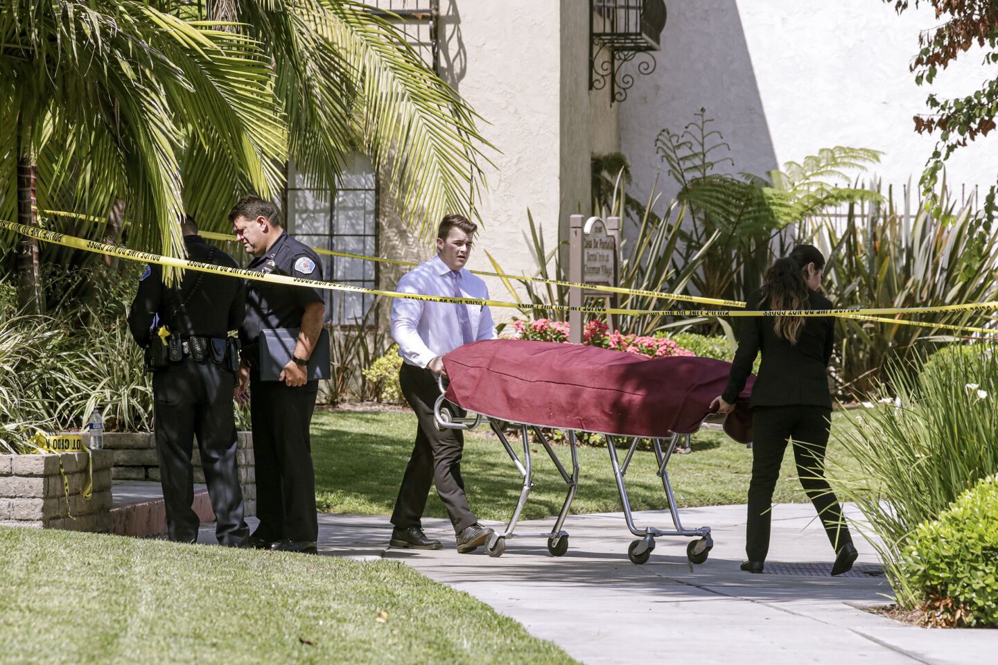 Coroners remove the body of a stabbing victim from the Casa De Portola apartment complex in Garden Grove.