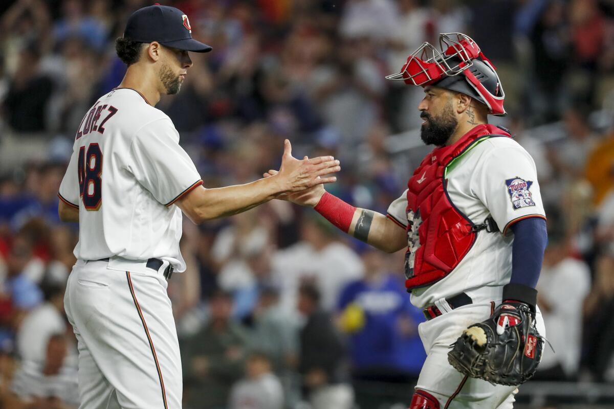 Minnesota Twins relief pitcher Jorge Lopez, left, celebrates a win over the Toronto Blue Jays with Sandy Leon, right, after a baseball game Saturday, Aug. 6, 2022, in Minneapolis. (AP Photo/Bruce Kluckhohn)