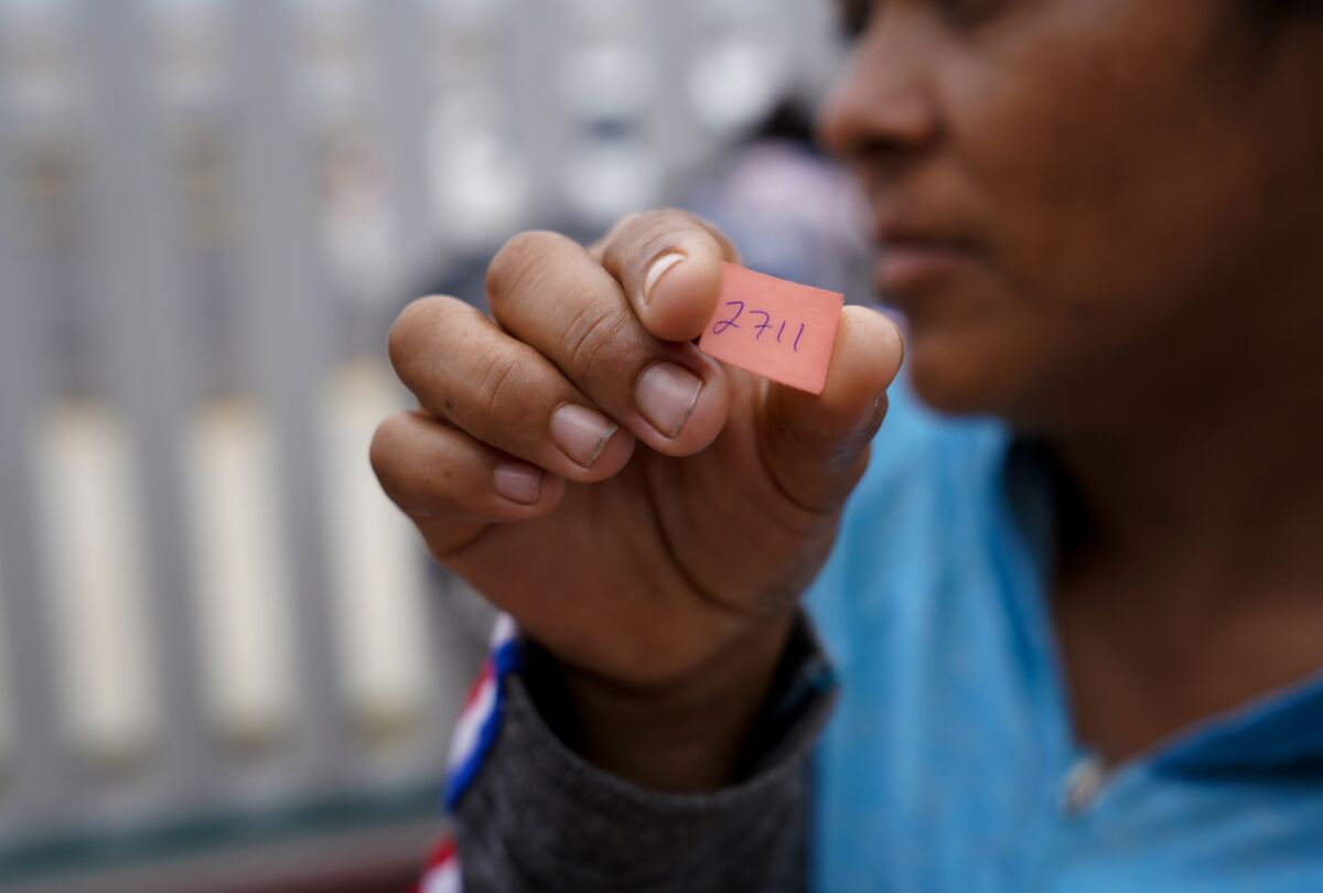 After waiting four-months in Tijuana, Abelina Morillo Vazquez, 33 from Mexico holds up her number as she and others wait in Tijuana at the Mexico - U.S. border on Tuesday July 16th 2019 hoping for their numbers to be called so they can can officially submit their application for asylum in the U.S.