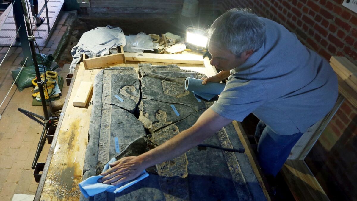 Conservator Jonathan Appell works to clean a 6-foot black stone slab that was discovered in the 1617 church at historic Jamestown, Va.