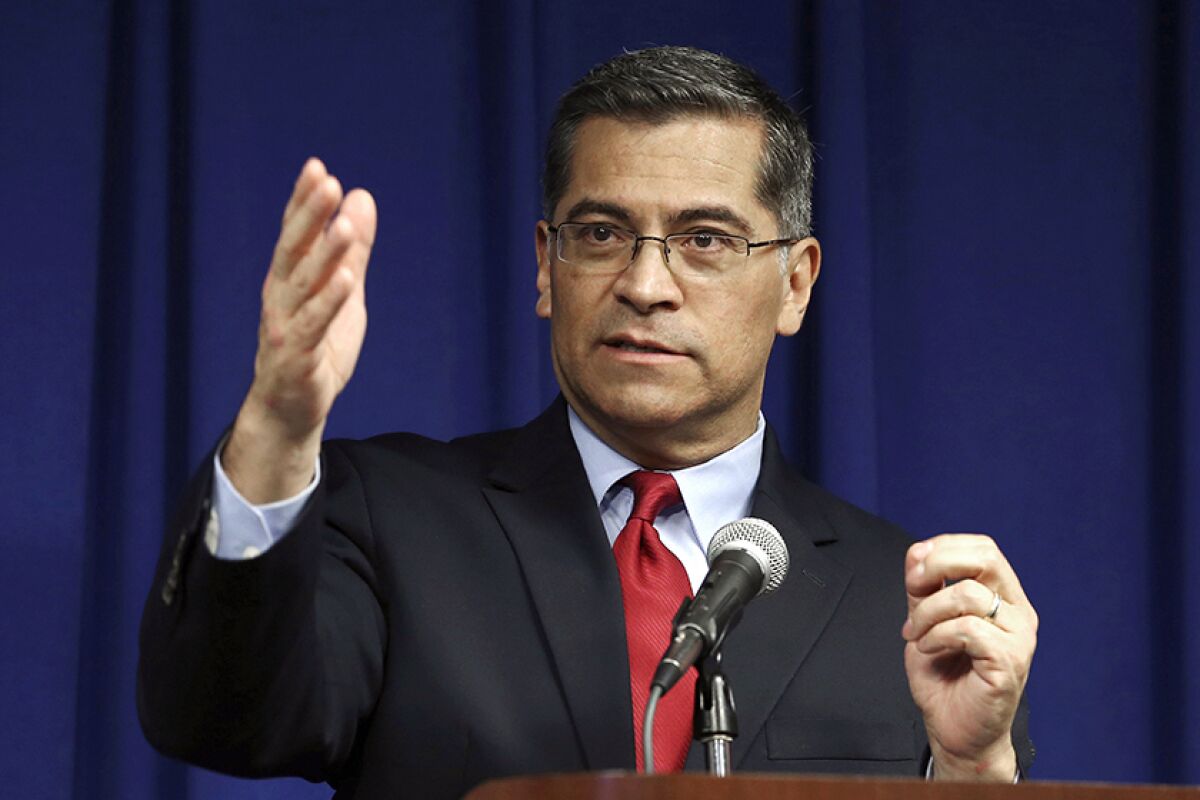 Xavier Becerra gestures as he speaks into a microphone.