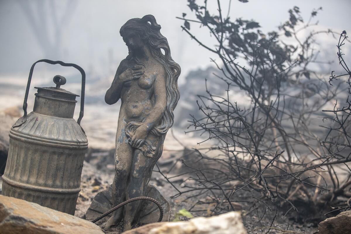 A statue singed by flames sits amid a home destroyed in the Bear fire on Thursday in Feather Falls, a town in Butte County. 