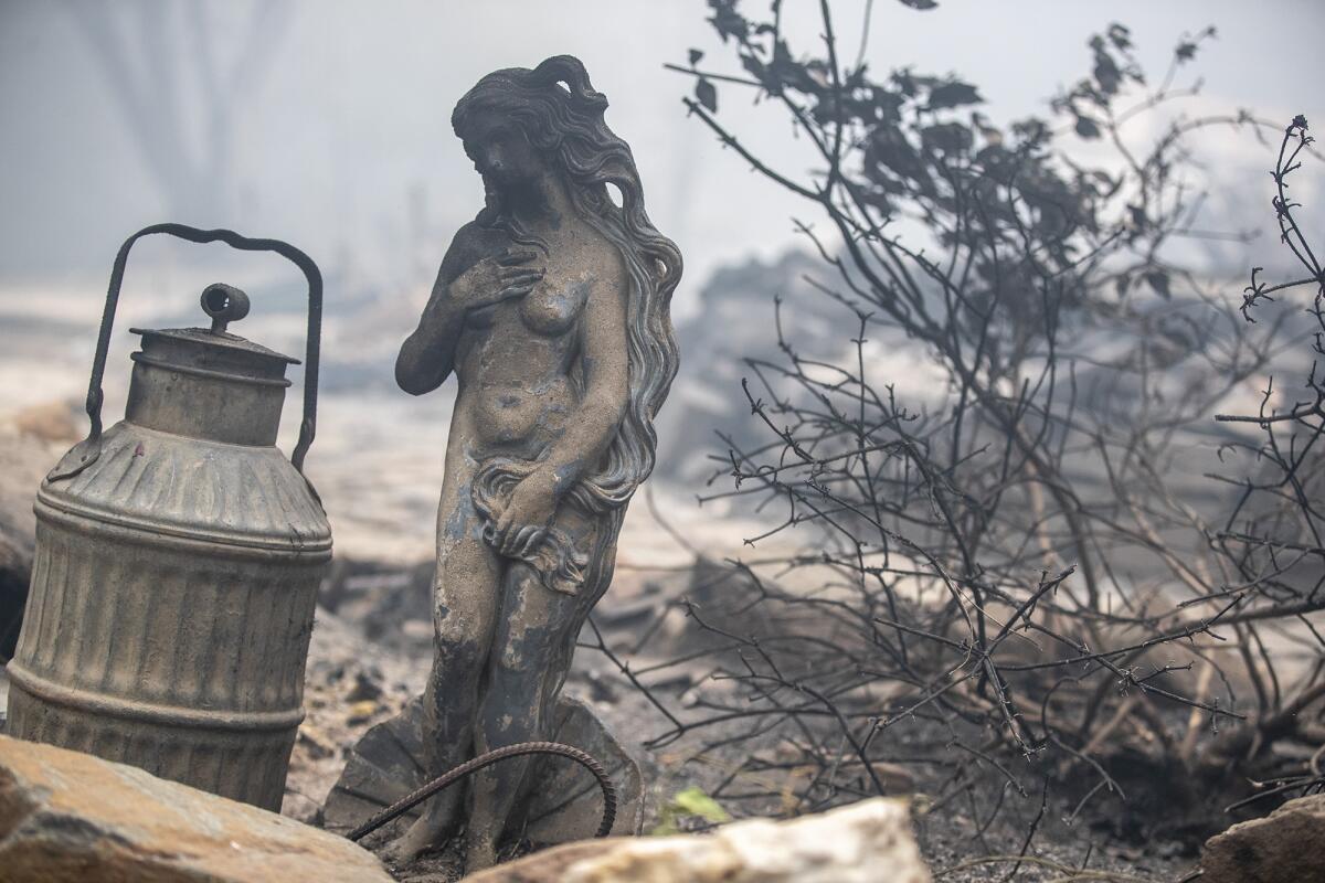 A statue singed by flames sits amid a home destroyed in the Bear fire on Thursday in Feather Falls, a town in Butte County.