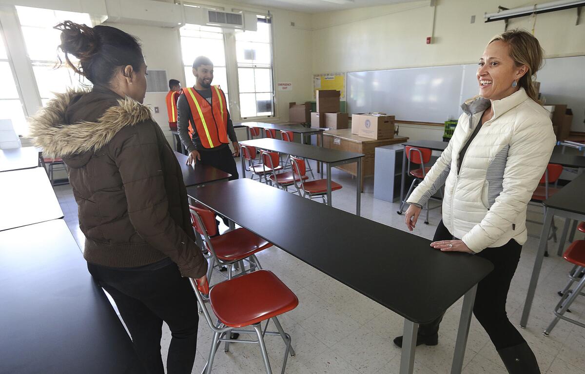 Porter Ranch Community School science teacher Rosie Van Zyl moves tables into position with the help of other LAUSD employees in her new classroom at Northridge Middle School.