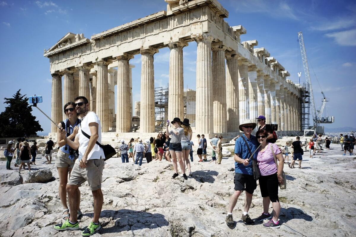 Tourists visit the ancient Acropolis hill, with the ruins of the fifth century B.C. Parthenon temple on June 30 in Athens.