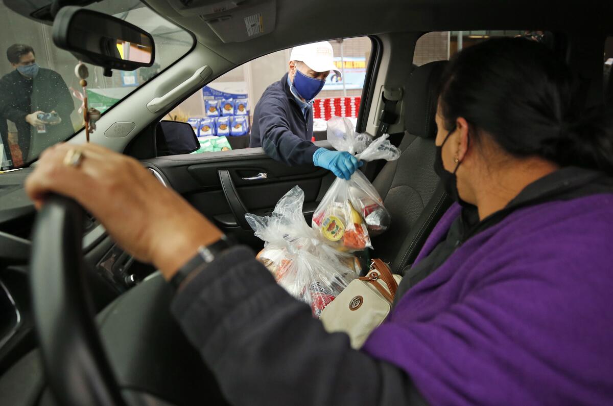 L.A. Unified Supt. Austin Beutner places bags of food in the passenger seat of Manuela Antonio's car.