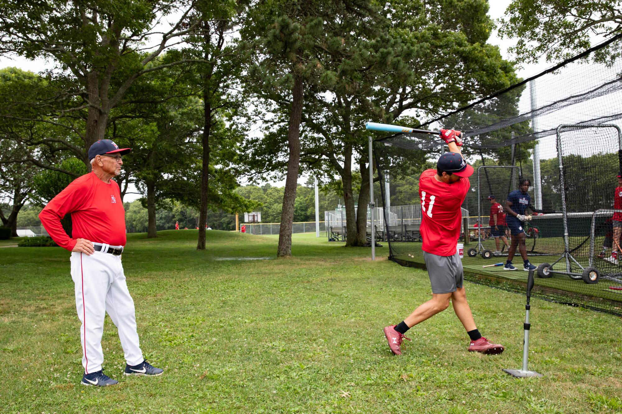 Coach Scott Pickler works with Will Tippett while he swings a bat. 