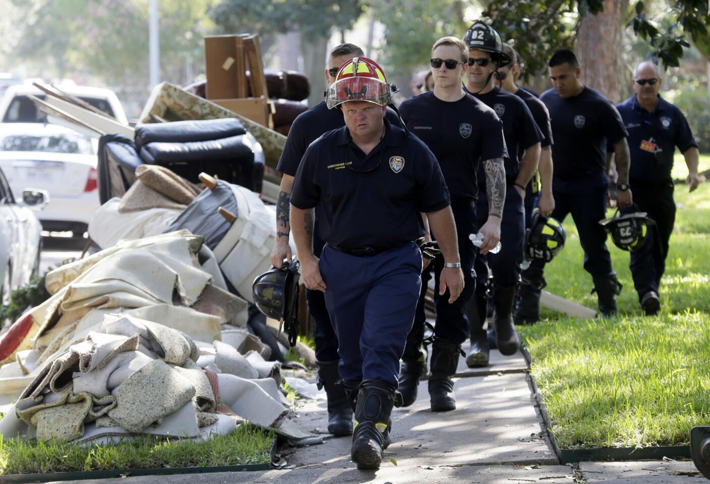 Bomberos caminan el jueves 31 de agosto de 2017 junto a escombros removidos de casas durante una bÃºsqueda puerta por puerta en un vecindario que fue azotado por las inundaciones que la tormenta tropical Harvey provocó en Houston, Texas. (AP Foto/LM Otero)