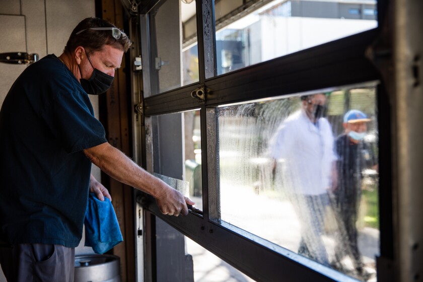 Bolt Brewery owner Clint Stromberg cleans the windows of his restaurant in Little Italy on Saturday, Dec. 19.