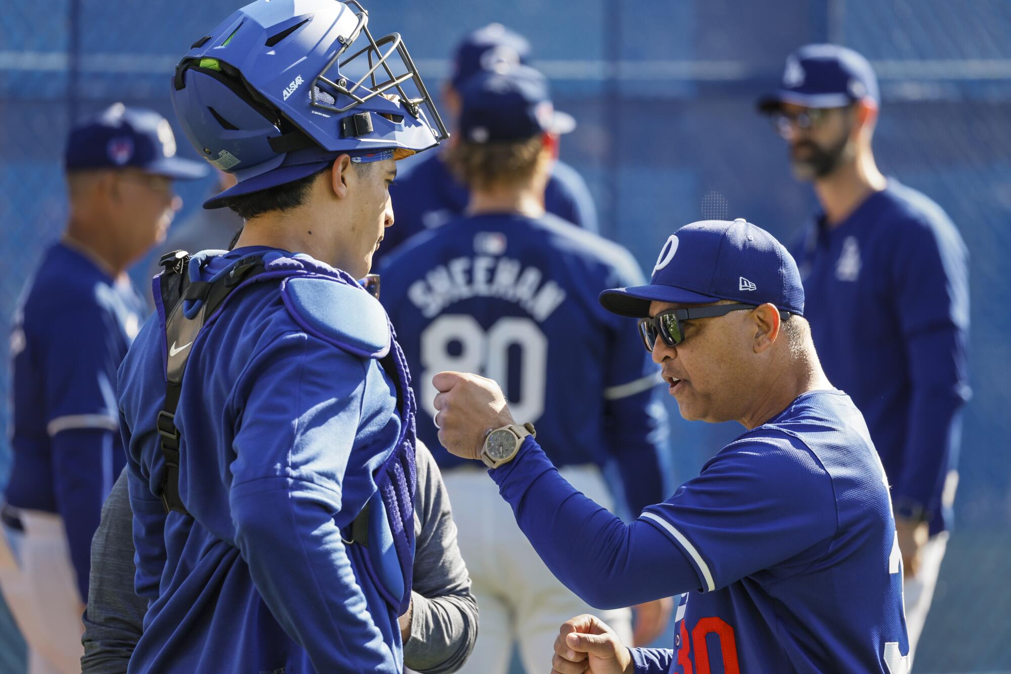 Dodgers manager Dave Roberts delivers a spirited talk to catcher Diego Cartaya at a spring training workout.