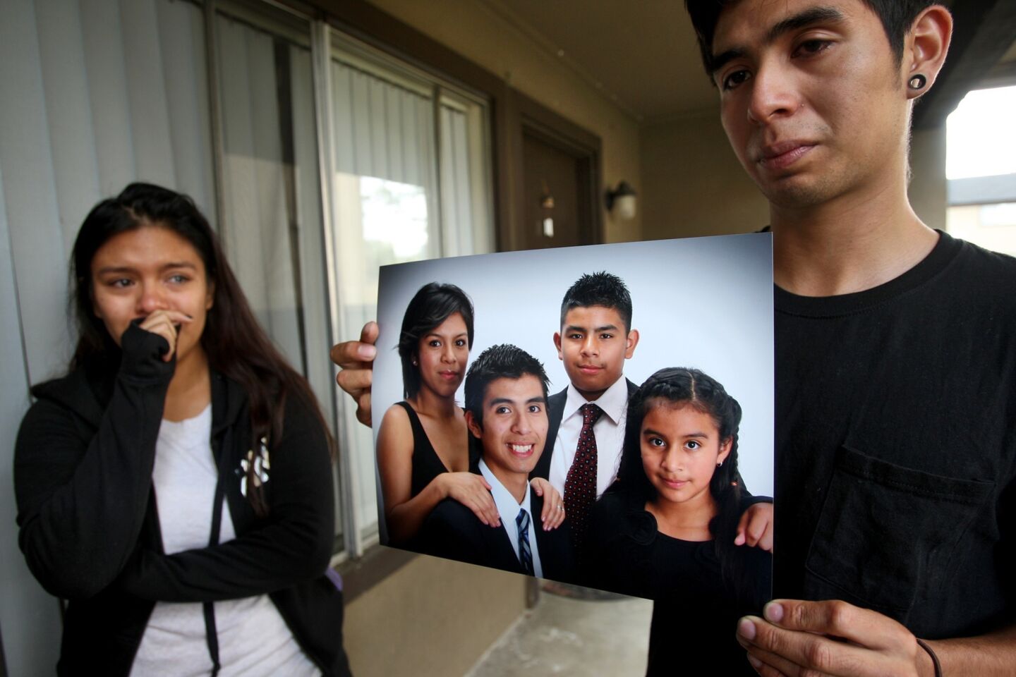 Brenda Gonzalez, 24, left, sobs as her 21-year-old brother holds a photo of their siblings. Hit-and-run victim Andrea Gonzalez, 13, is seen at right.