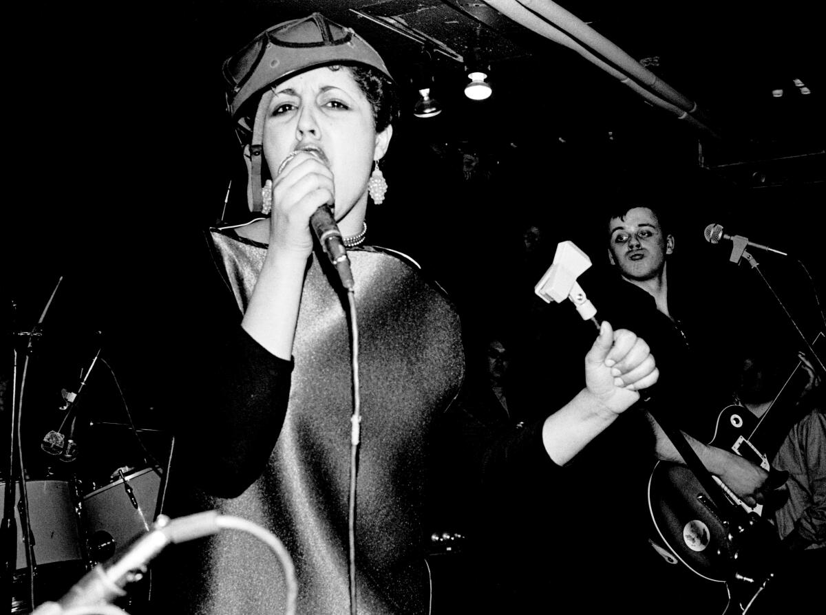 A woman singing onstage with a punk band