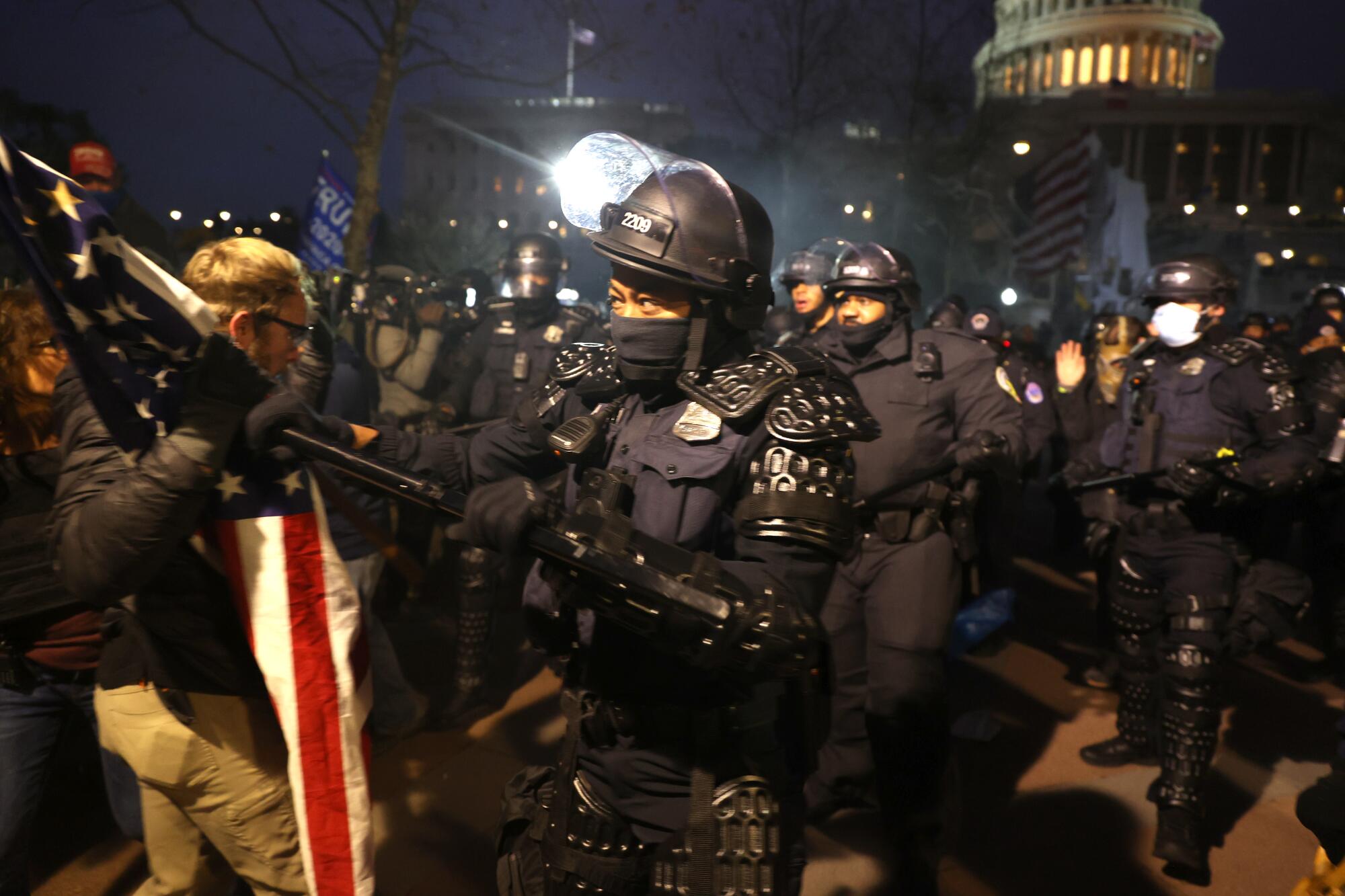 Police officers in riot gear confront Trump supporters outside the U.S. Capitol.