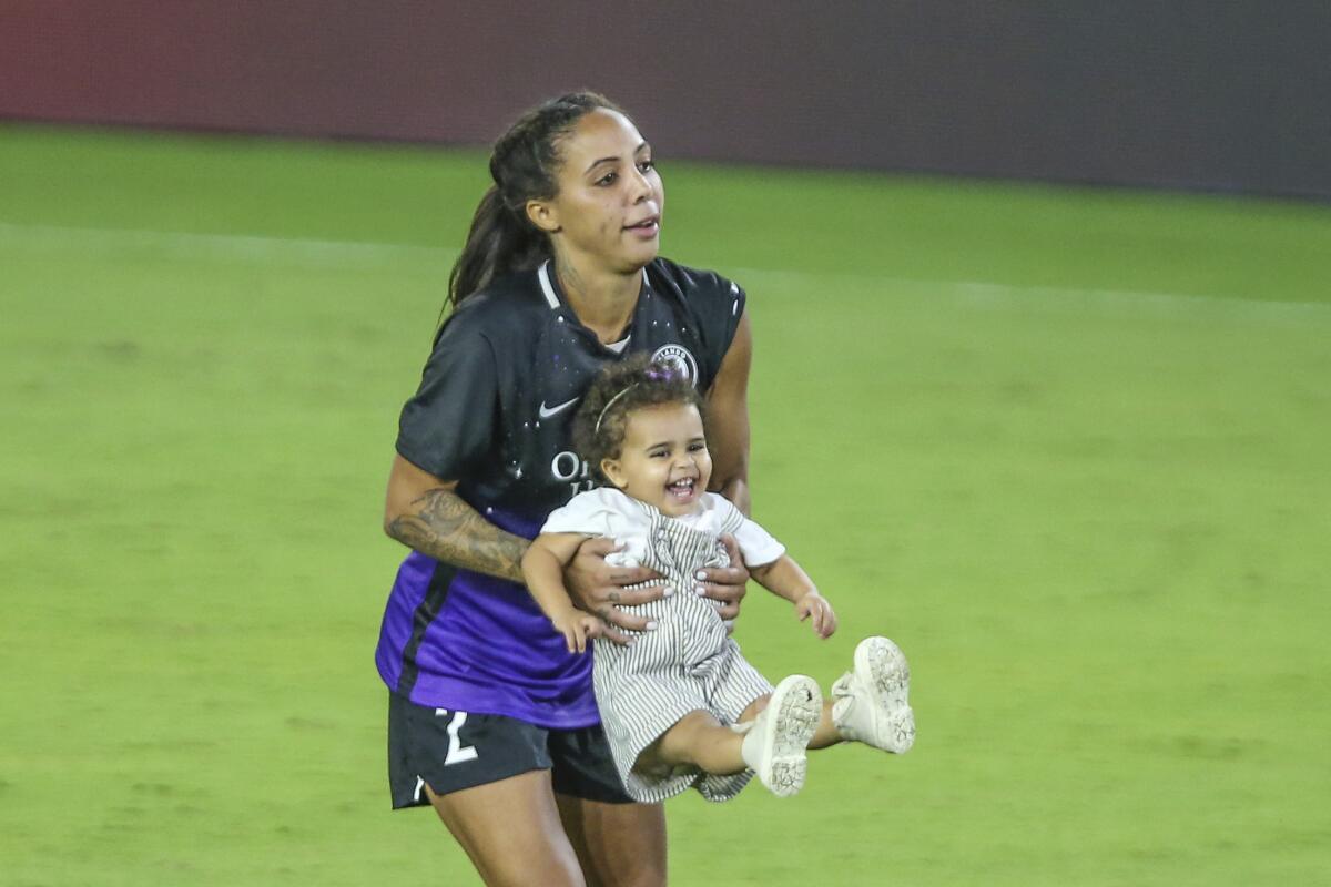 Orlando Pride forward Sydney Leroux swings her daughter, Roux, on the field after a match