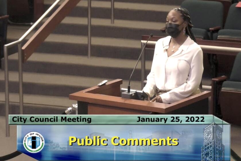 A woman in a mask speaks at a lectern during a City Council meeting