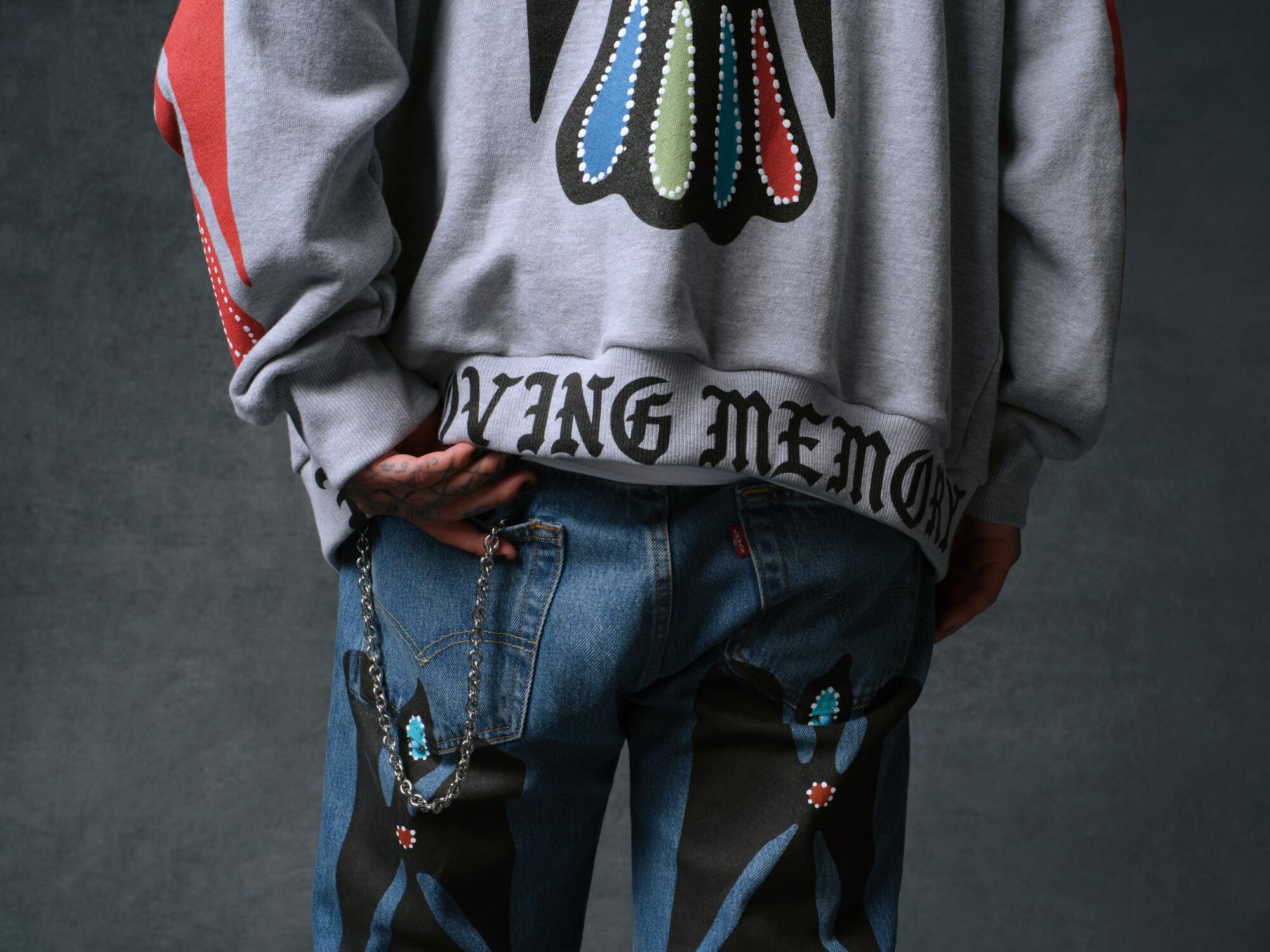 A person wears a sweatshirt with the words "In loving memory" embroidered