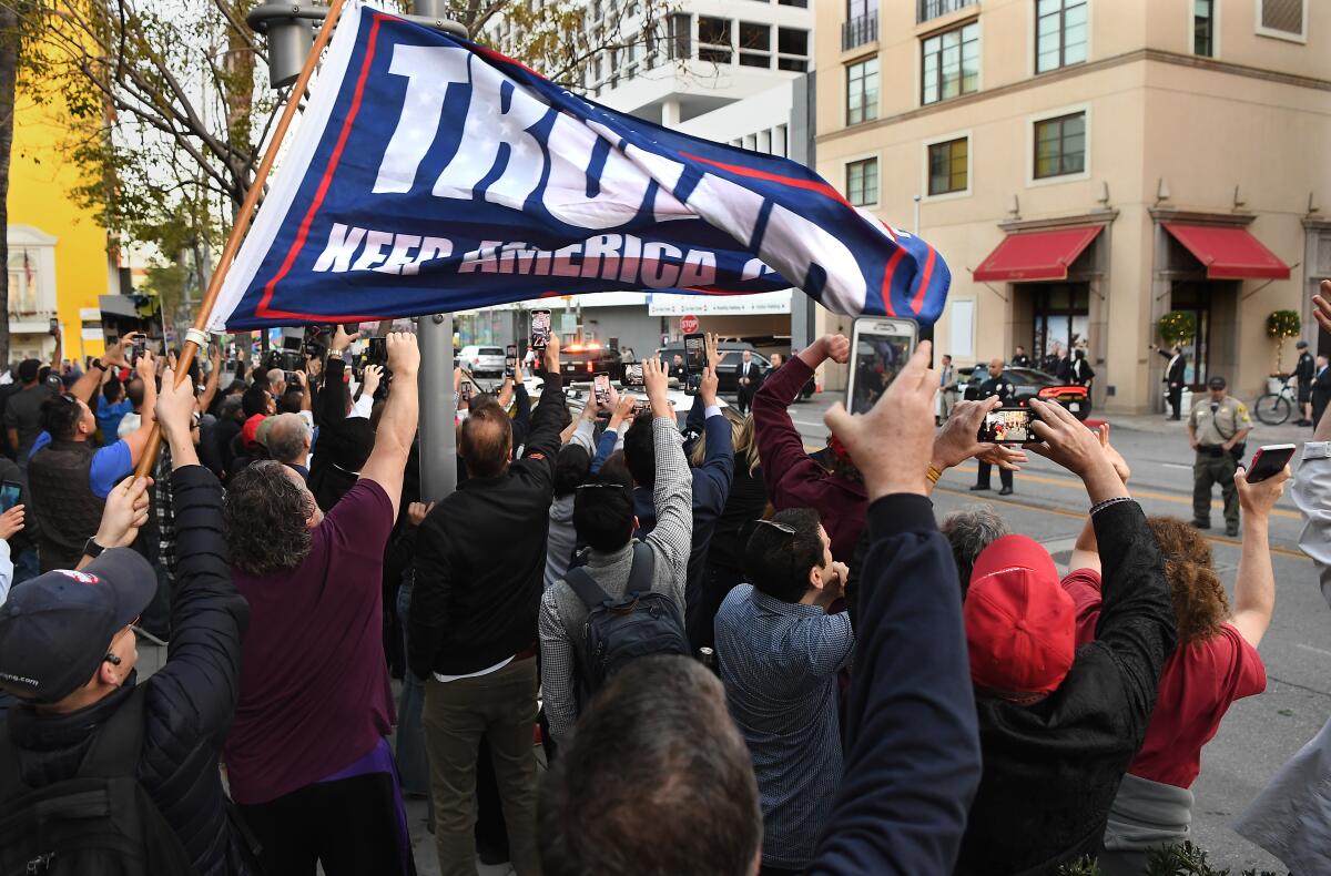 Trump supporters and protesters watch as the president arrives outside the Montage Hotel in Beverly Hills