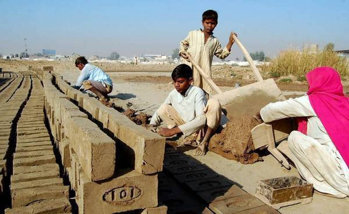 In Multan, Pakistan, Shahbaz, 10, unloads a cart of mud that will be made into bricks by his mother, Nazira Bibi, brother Shahzad and father, Mohammed Sadiq.