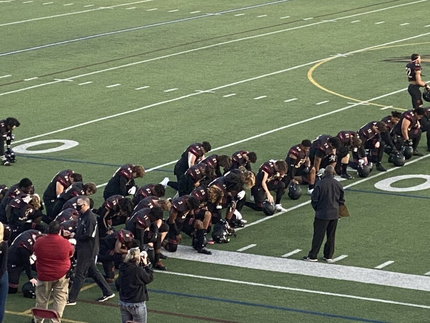 Oaks Christian players kneel for a pregame prayer before their 30-16 win over Westlake.