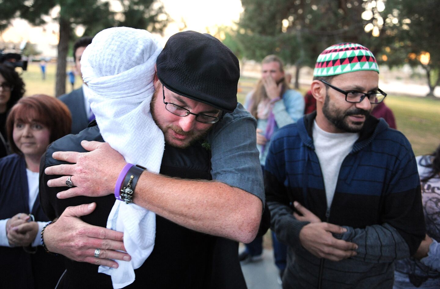 Ryan Reyes, boyfriend of San Bernardino shooting victim Larry Daniel Kaufman, hugs members of Dar Al Uloom Al Islamiyah of America mosque who brought roses to a memorial at the Sante Fe Dam on Saturday.
