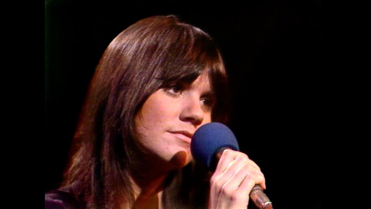 Close-up of a woman with brown hair holding a microphone