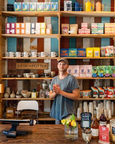 A person stands in front of shelves full of colorful merchandise at the Canal Market in Venice.