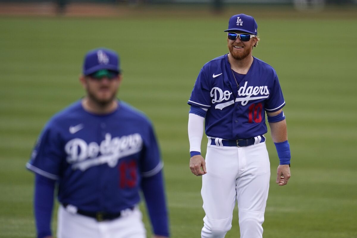 Dodgers third baseman Justin Turner, right, smiles while warming up with teammate Max Muncy.