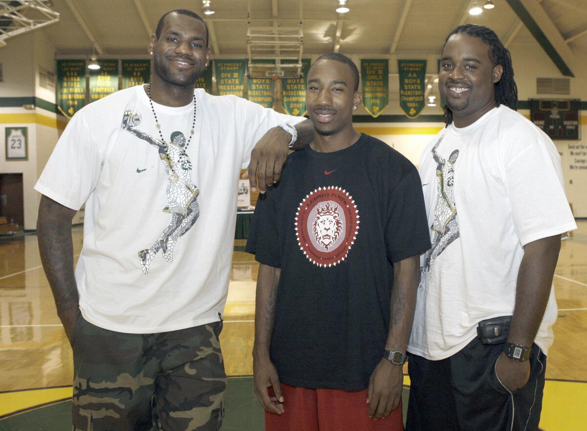 Former St. Vincent-St. Mary High teammates LeBron James, Dru Joyce III and Willie McGee stand in their high school gym 