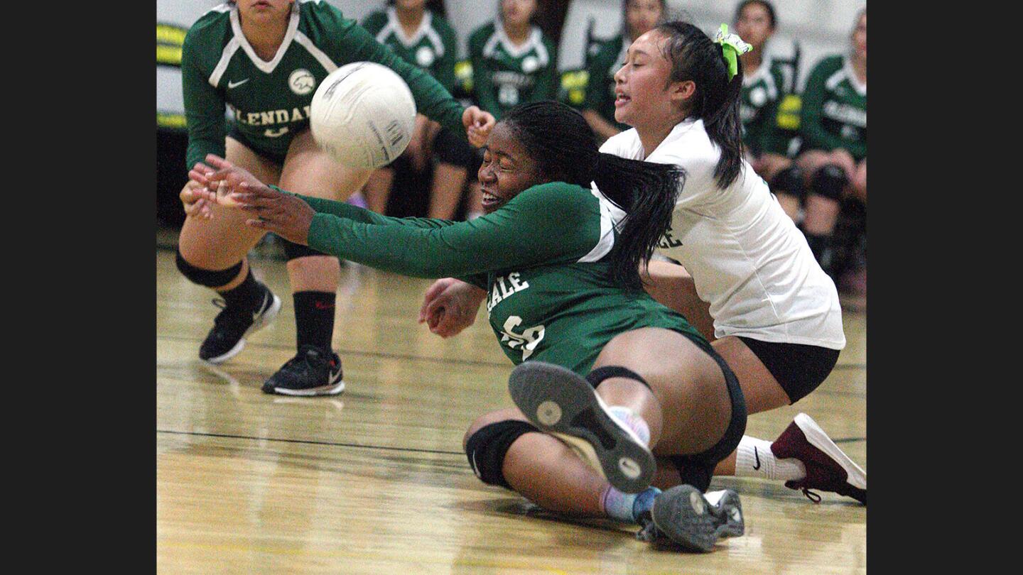 Glendale Adventist Academy's Paige Singleton and Camille Pizarro fall to the floor together to keep a serve in play against Orangewood in a non league girls' volleyball match at Glendale Adventist Academy on Monday, September 18, 2017.