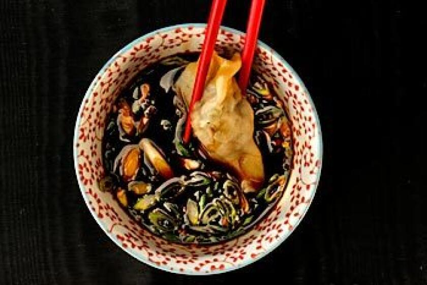 A handmade shrimp dumpling is dipped in black vinegar seasoned with soy sauce.