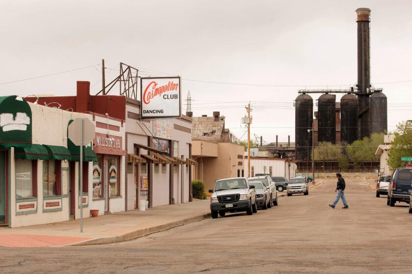 A man walks across the street in a portion of town with a view of a bit of the Steel Mill complex in the background in Pueblo, Colorado on Tuesday, April 25, 2017. Photographer: Matthew Staver AssignID: 2675786 Assign Name: 2675786_la-na-trump-100-days-pueblo Slug: la-na-trump-100-days-pueblo Story is about President Donald Trump's first 100 days in office. We talk to people in Pueblo which was once a Democratic stronghold. Need a overall scene setter of the town including the downsized steel mill.