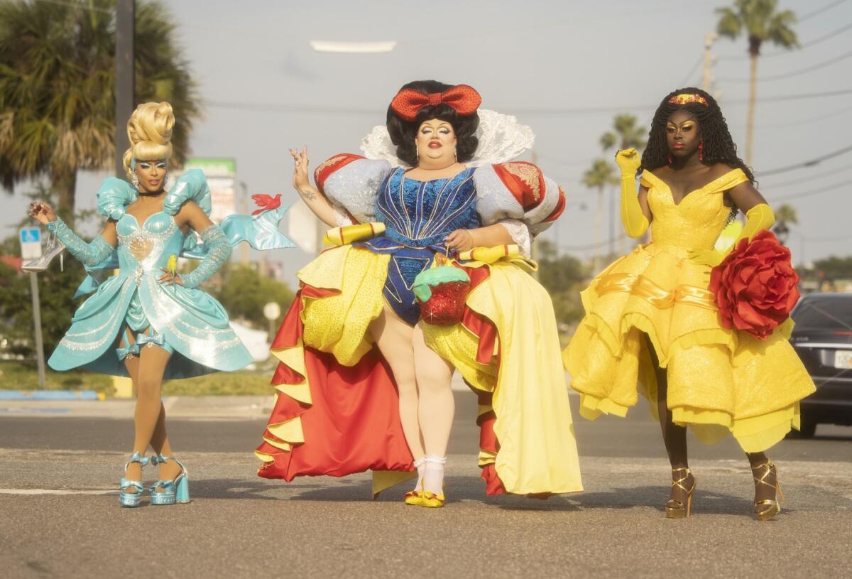 Drag queens strike poses in dresses evoking Disney fairies and princesses.